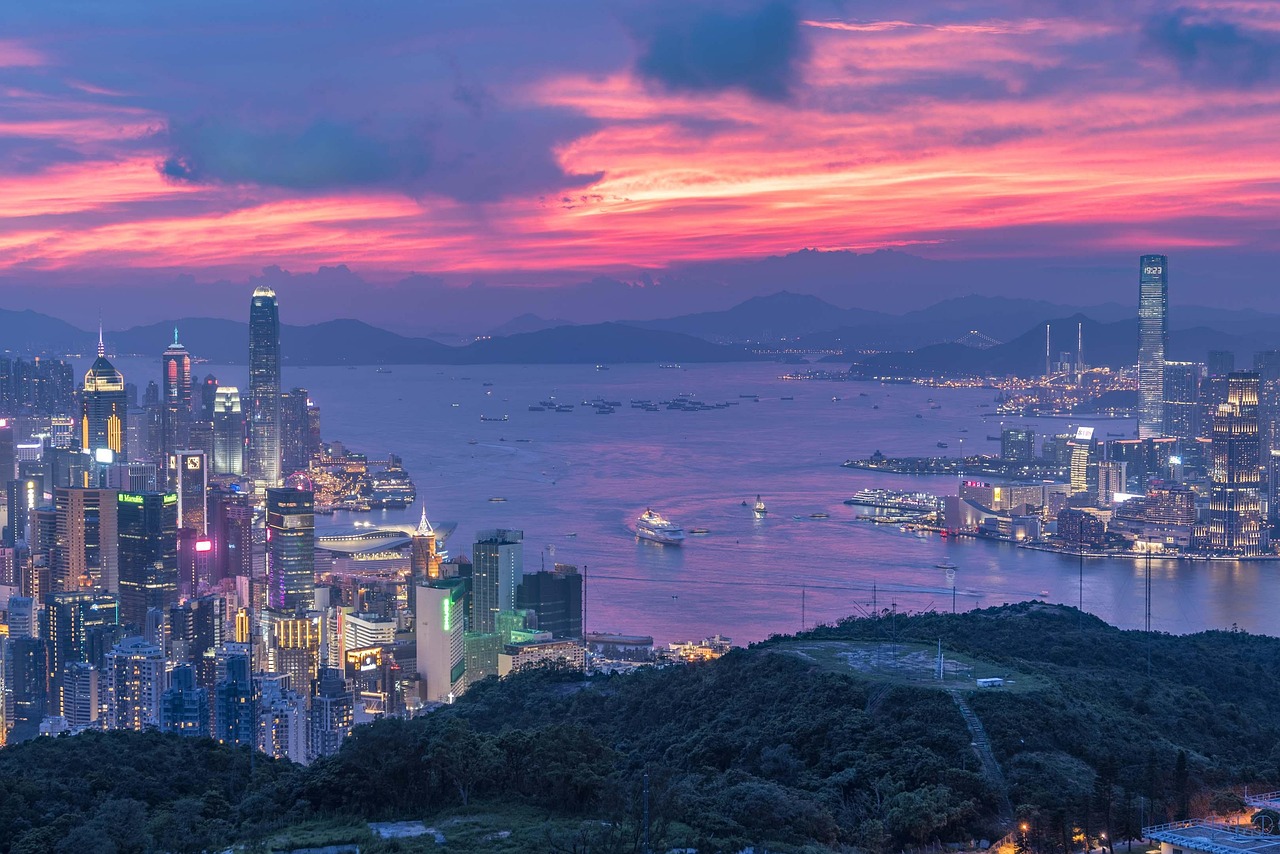 Evening view of a city skyline of skyscrapers rising over a busy harbour at sunset